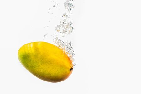Mango fruit splashing into water, isolated on white background.の写真素材