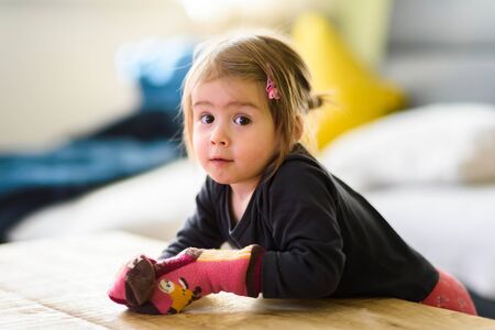 Two year old girl with big eyas portrait looking at camera with socks on her hands, Indoor shoot...
