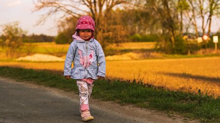 Cute little girl having fun at countryside portrait on sunset. Child in nature exploringの写真素材