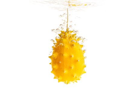 Kiwano or Horned Melon Cucumis metuliferus detailed skin shoot splashing into water on white background.の写真素材