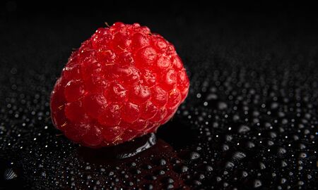 One fresh raspberry closeup on a black background isolated. Detailed shootの写真素材