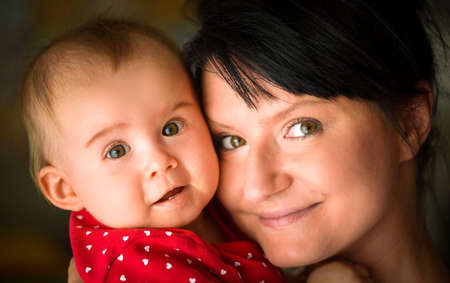 Young mom with her 9th month old daughter cuddling on portrait. Natural light shoot of family