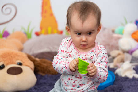 Sweet 1 year old baby girl portrait with rubber chew toy in her bright room