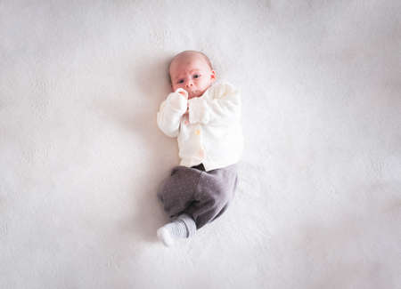Sweet 1 month old baby girl lying on the bed at home, top view. Selective focus. Copy space.