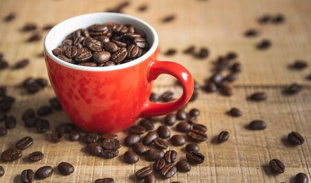 A cup full of coffee beans on a wooden mangocoffee table. Coffee conceptの写真素材