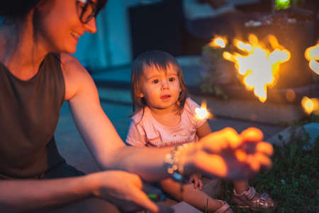 Child seeing sparkler fireworks first time outside. Happy and excited 2 years old.の写真素材