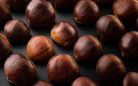 Rows of chestnuts isolated on black background. Chestnuts theme