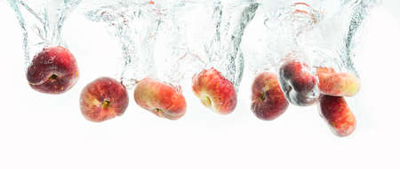 Bunch of doughnut peaches isolated on white background, splashing into water.の写真素材