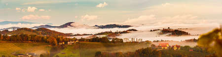 South styria vineyards panorama, Tuscany of Austria. Sunrise in autumn. Colorful trees and vieyard at top of hill with poplar treesの写真素材