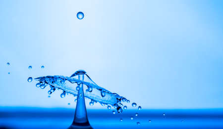 Water drop splashing into blue water surface. Health and purity concept