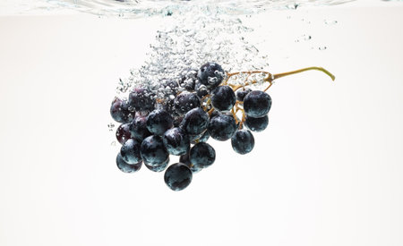 Bunch of blue grapes sinking underwater with splash.の写真素材