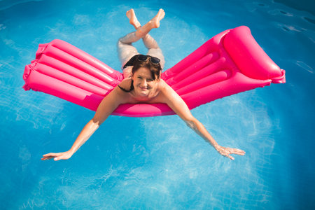 Young woman on pool air mattress in above ground pool.