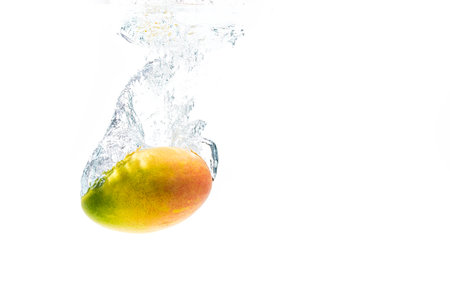 Mango fruit splashing into water, isolated on white backgroundの写真素材