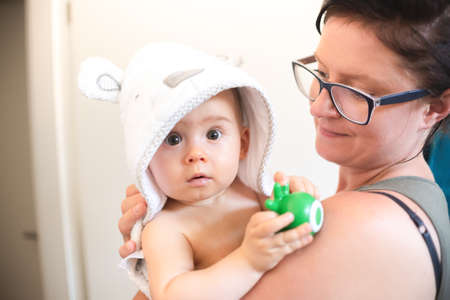 Mother holding baby with bathrobe after eavning bath. Baby hygiene and healthcare.の写真素材