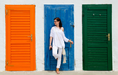 Young woman standing against colorful doors. Lifestyle background