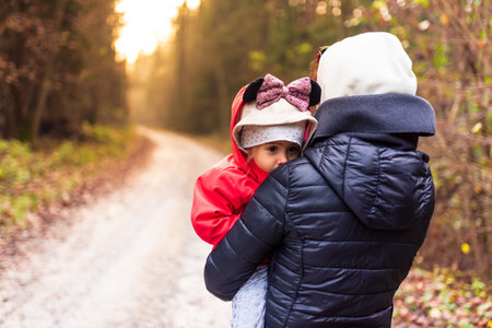 Mother holds baby girl in arms in moody forest. Outdoors backgroundの写真素材