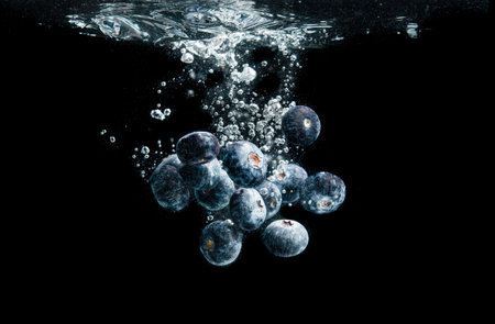 Blueberries splashing in water on black