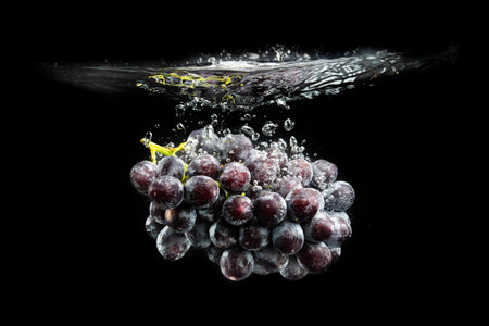 Isolated Red grapes splashing and sinking in water on blackの写真素材