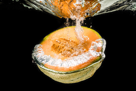 Half of Orange cantaloupe melon sinking, isolated on blackの写真素材