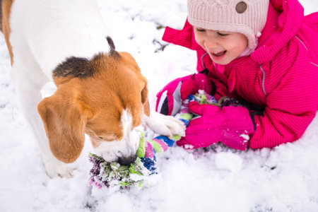 Child playing with dog on snow.の写真素材