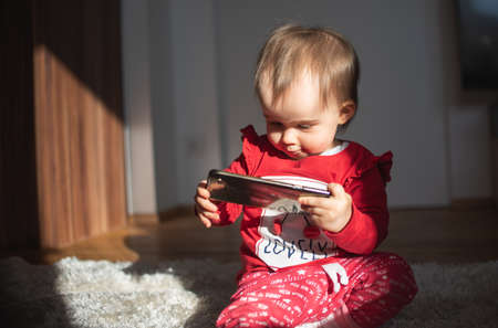 Baby holding smartphone in bright interiorの写真素材