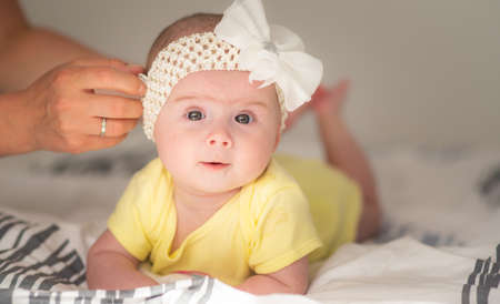 Cute baby portrait girl on bed in bright interior.の写真素材