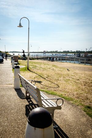 A green wooden bench standalone on the San Remo beach side recreational area in Melbourne, Australiaの写真素材