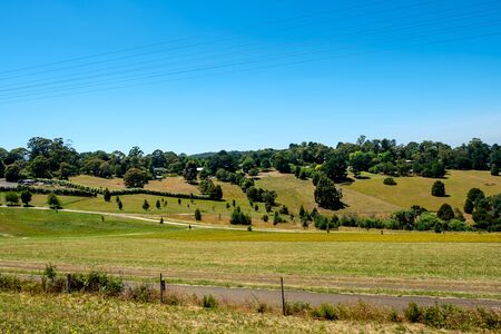 A rural side road with beautiful grassland, trees, and beautiful sky in Melbourne, Australiaの写真素材