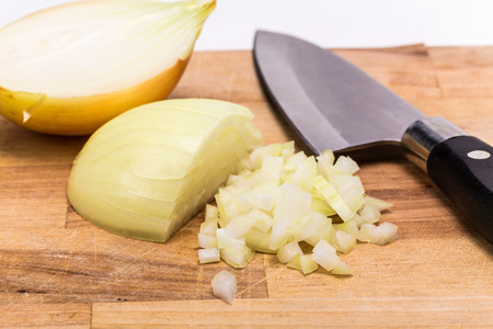 Chopped onion with knife on a wooden boardの写真素材