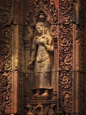 Lovely Apsara (dancing woman) red sandstone carving at the Banteay Srei temple (temple of women) near Angkor Wat (Siem Reap, Cambodia).の写真素材