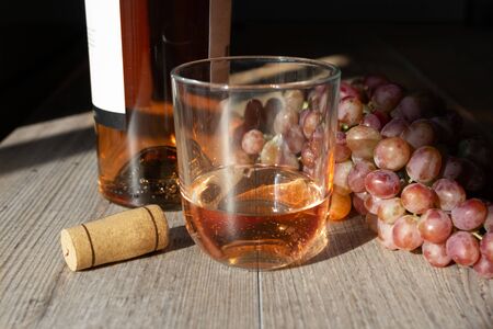 sunbeam illuminated glass of wine, bottle and cork stopperの写真素材