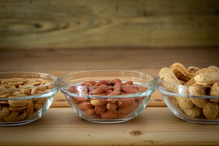 peanuts in 3 glass bowl on wooden cutting boardの写真素材