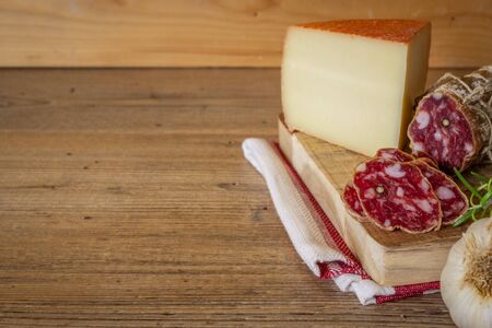 Salami and cheese slices on wooden tableの写真素材