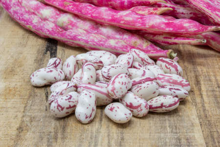 pinto beans and pinto beans in pods on wooden background