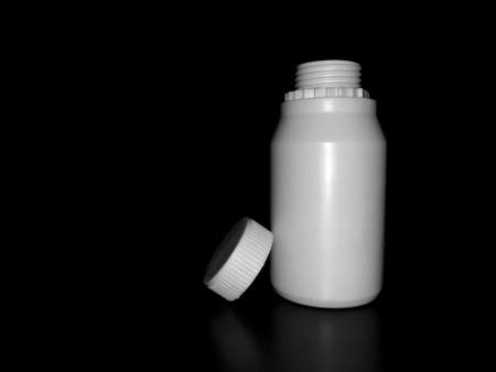 The empty plastic white bottle is on a dark background.の写真素材
