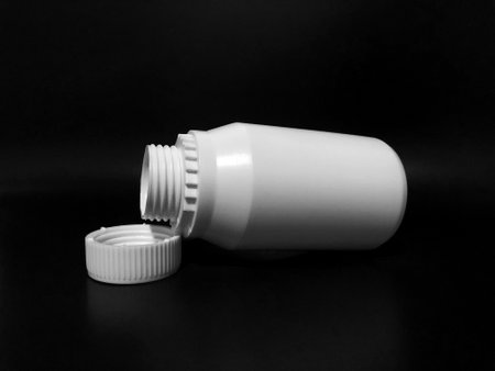 The empty plastic white bottle is on a dark background.の写真素材