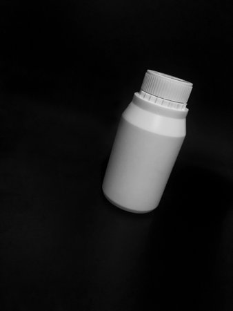 The empty plastic white bottle is on a dark background.の写真素材