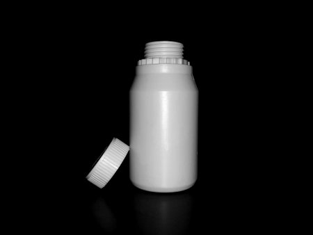 The empty plastic white bottle is on a dark background.の写真素材