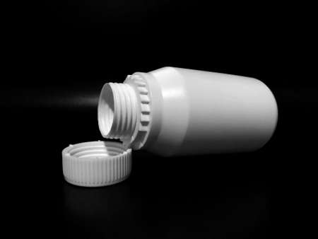 The empty plastic white bottle is on a dark background.の写真素材