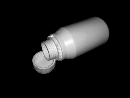 The empty plastic white bottle is on a dark background.の写真素材