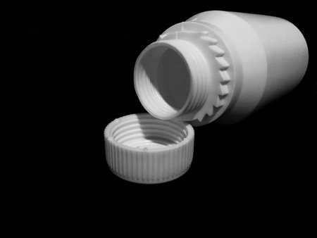 The empty plastic white bottle is on a dark background.の写真素材