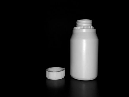 The empty plastic white bottle is on a dark background.の写真素材