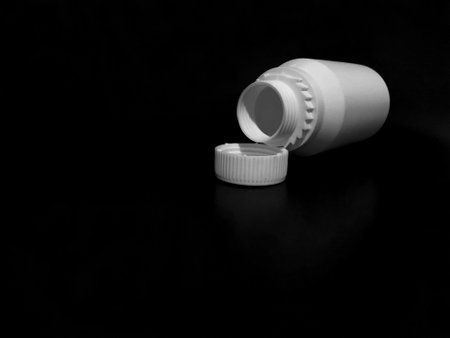 The empty plastic white bottle is on a dark background.の写真素材