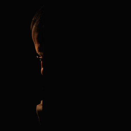 Middle aged man thinking, emerging from behind dark wallの写真素材