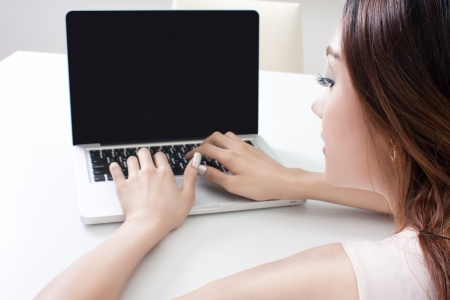 Rear-view of woman working on laptop indoorsのeditorial素材