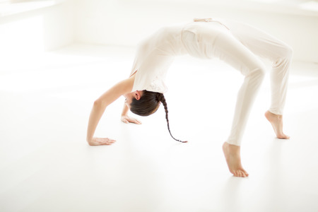 Young Caucasian woman doing yoga in sunny room.