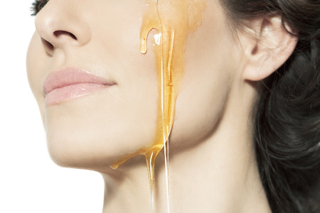 Closeup of a female cheek with honey.の写真素材