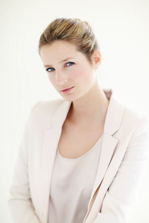 Young Caucasian businesswoman wearing powder pink blazer posing indoors.の写真素材