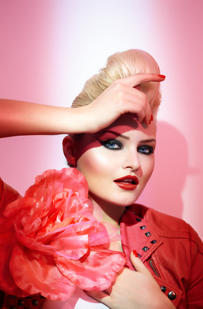 Female model posing in pink light and wearing pink leather jacket with a huge rose.の写真素材