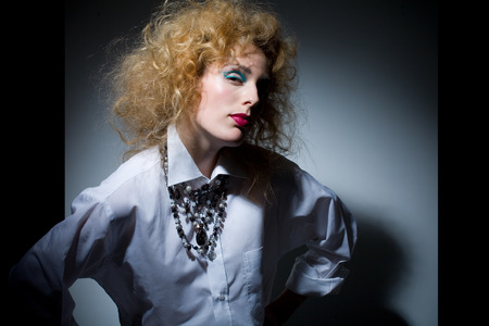 Model with fluffy hair wearing white shirt and jewelry.の写真素材